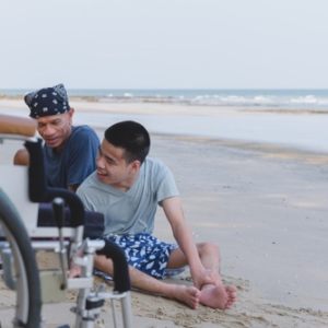 teenage boy with cerebral palsy playing at the beach with his family