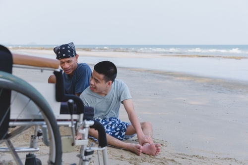 teenage boy with cerebral palsy playing at the beach with his family