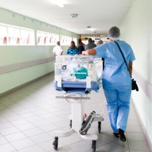 Image of a hospital hallway with a nurse pushing a pediatric hospital bed. Even in moments like this, systemic negligence can cause issues that increase the likelihood of patient injury.