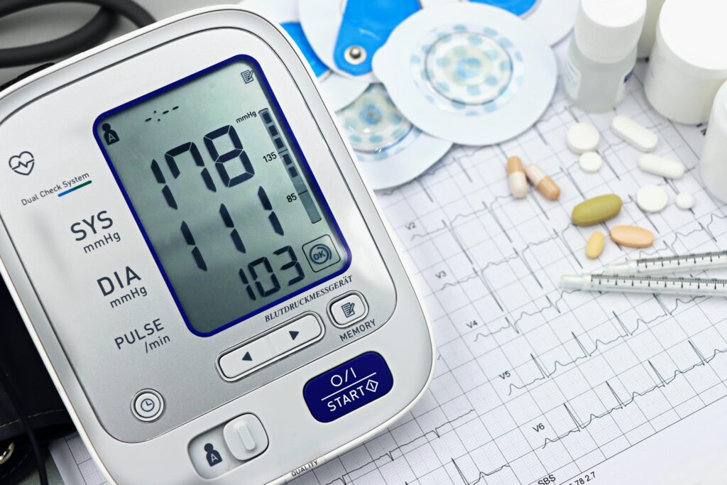 A blood pressure monitor showing high blood pressure next to medication and a heart tracings. Sometimes genetic causes are the root of such issues, but they are not always the cause of an injury while at a hospital.