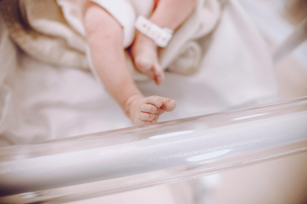 NICU staffing may contribute to catastrophic injury when understaffing leads to slow intervention or missed observation. Photo shows the feet of an infant in a NICU bed.