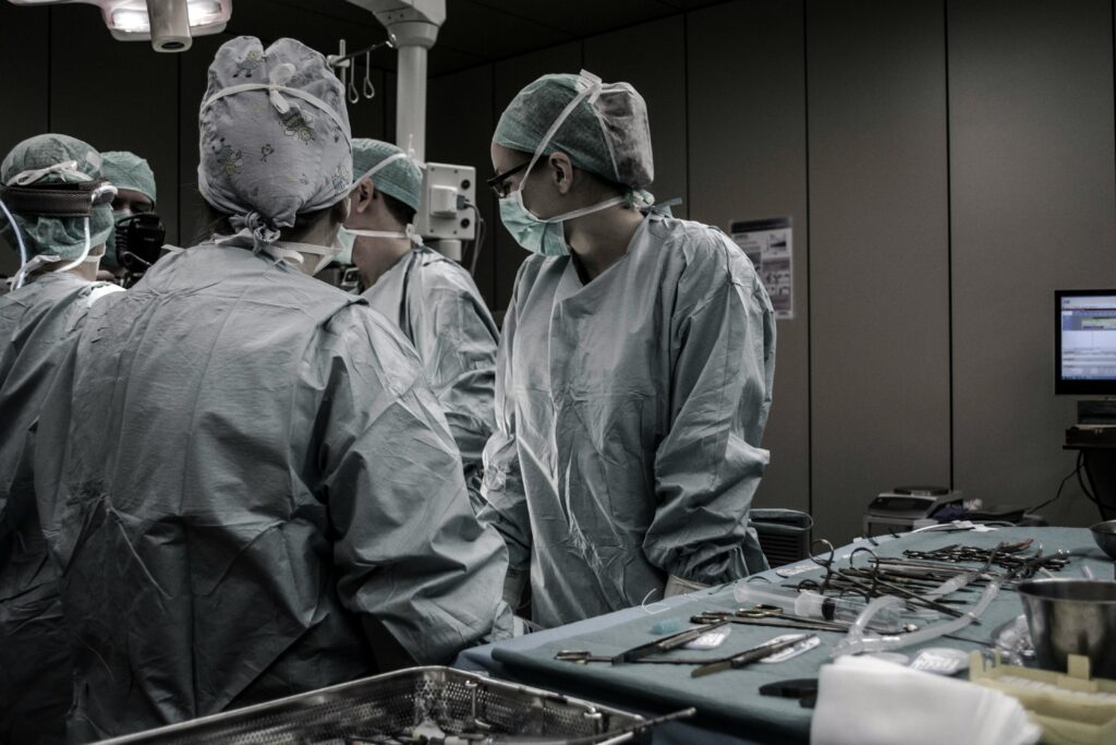 When negligence occurs in a hospital, determining who is at fault often involves discussions about corporate negligence vs. vicarious liability. Photo shows doctors in a dark operating room with medical tools nearby.