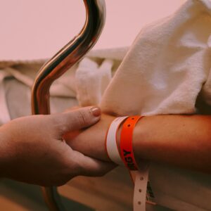 When neurosurgical intervention is delayed, it can have traumatic or catastrophic outcomes for the patient. Image shows someone holding a patient's hand.
