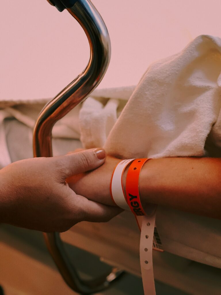 When neurosurgical intervention is delayed, it can have traumatic or catastrophic outcomes for the patient. Image shows someone holding a patient's hand.