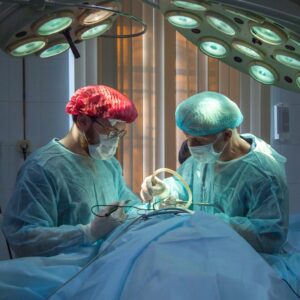 Two surgeons working on a patient, one in a red cap, the other in blue. This is symbolic of competing medical testimony, where two experts go head to head to try and explain how an injury occurred.