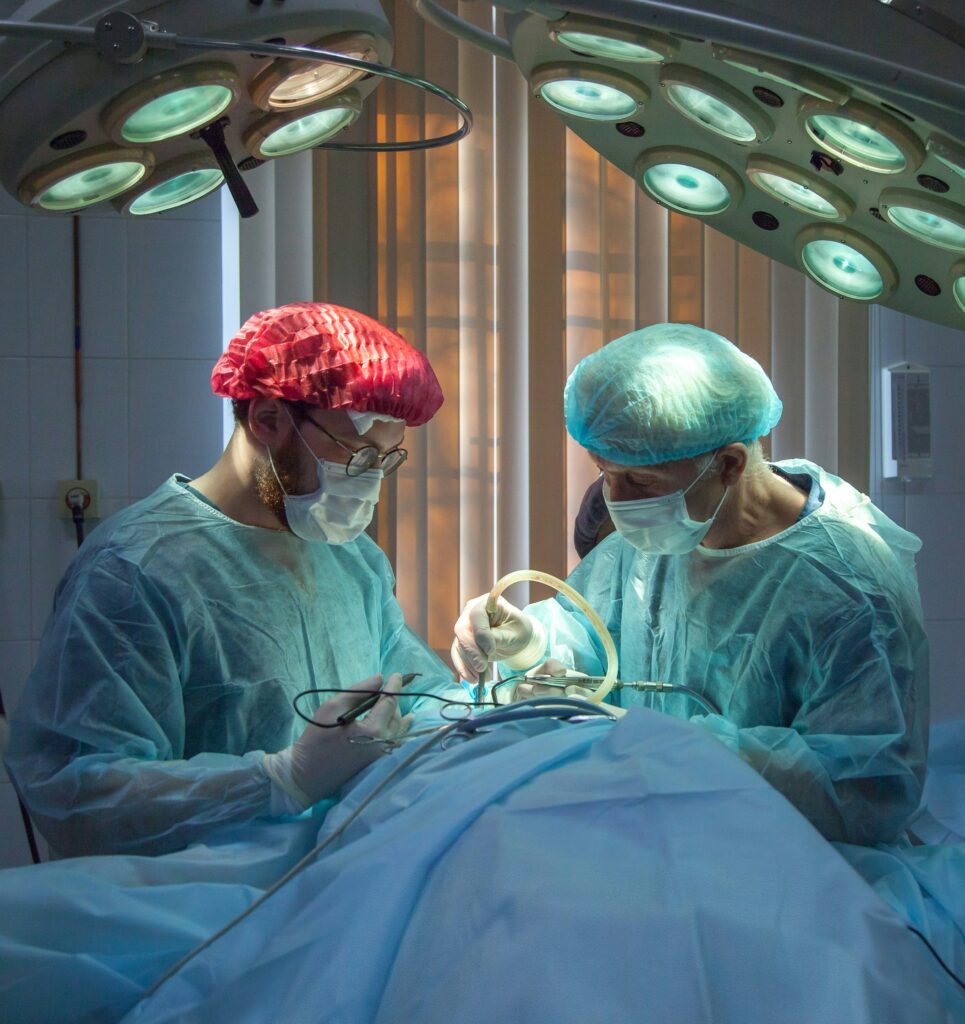 Two surgeons working on a patient, one in a red cap, the other in blue. This is symbolic of competing medical testimony, where two experts go head to head to try and explain how an injury occurred.