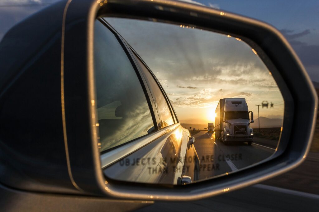 A truck visible in a car's rear view mirror. In certain truck accidents, it becomes clear that there is comparative negligence at play, where each driver played a role in the outcome.
