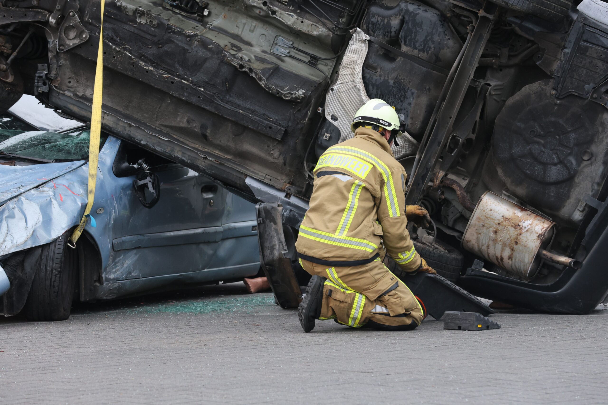 A firefighter studying a car that has been crushed under a tractor trailer. Crush injuries after a truck accident can cause extensive damage.