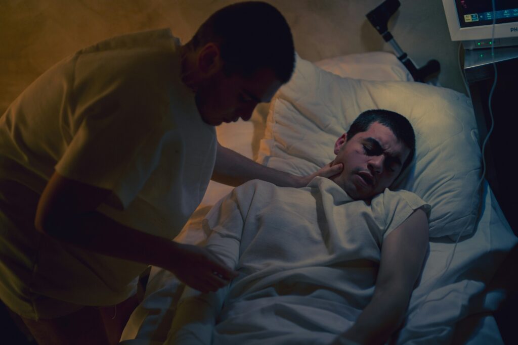 A patient in a dark room who is seemingly in pain. The cause may be retroperitoneal bleeding, which can occur after a traumatic incident.
