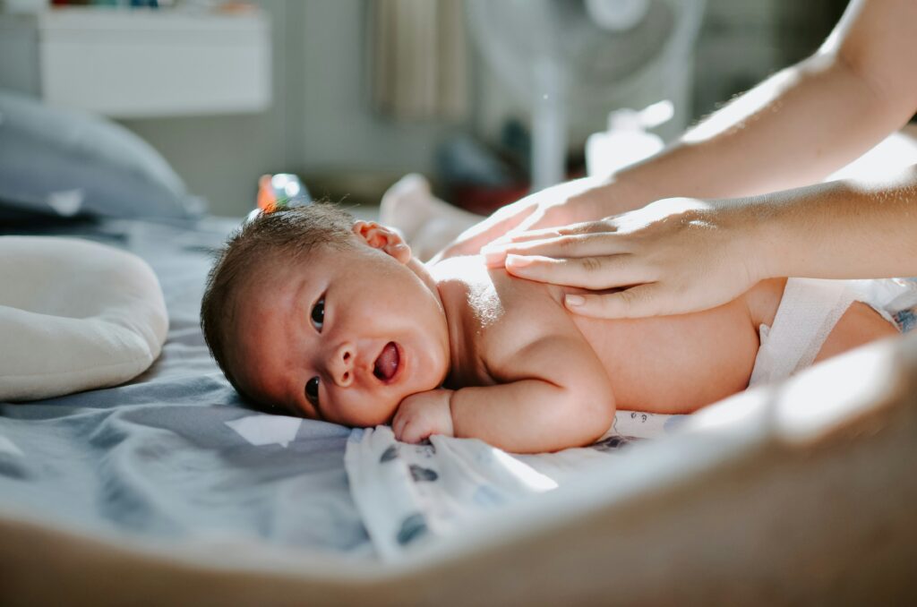 Meconium Aspiration Syndrome, where a neonate inhales meconium in the womb, can cause damages if left unnoticed or if intervention is delayed. Image shows a baby laying prone with a hand on their back.