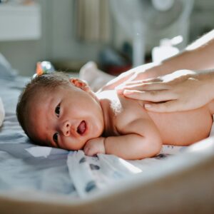 Meconium Aspiration Syndrome, where a neonate inhales meconium in the womb, can cause damages if left unnoticed or if intervention is delayed. Image shows a baby laying prone with a hand on their back.