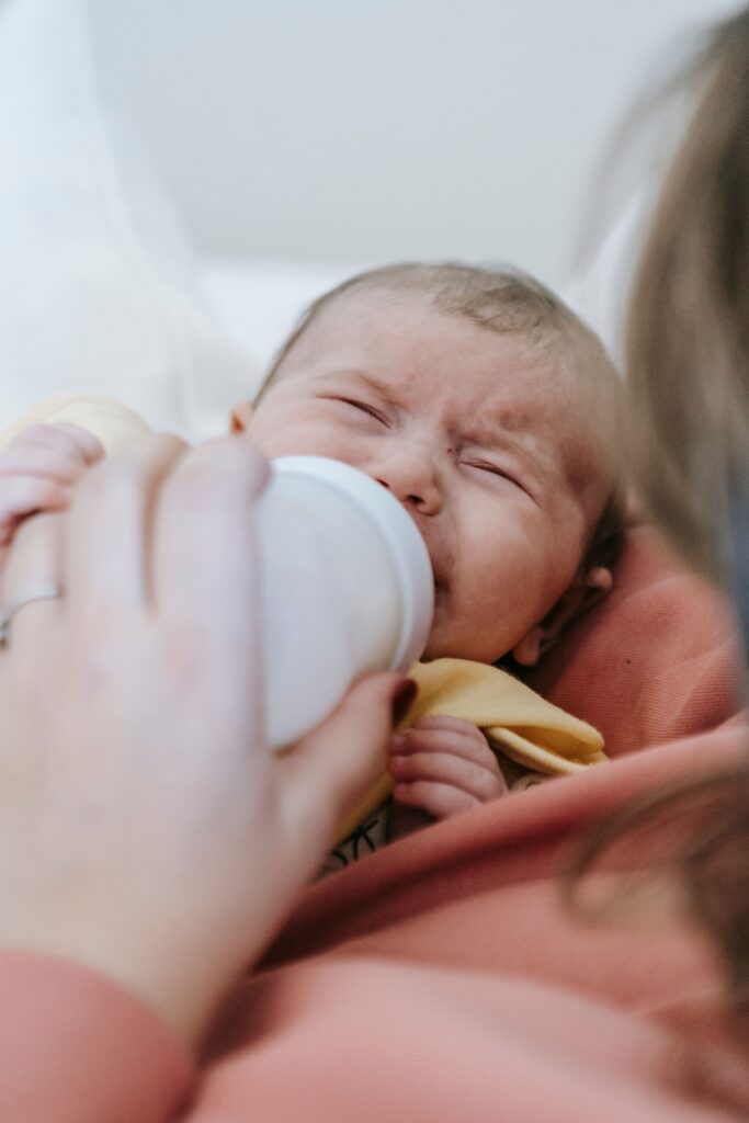 An infant struggling to drink milk, possibly caused by a condition known as galactosemia. The baby will need to be treated properly.